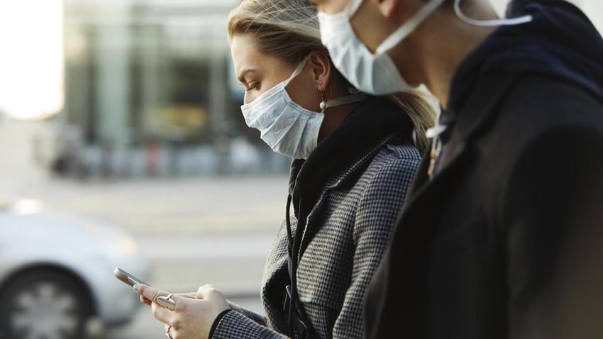 Two people in face masks walking outside in the city