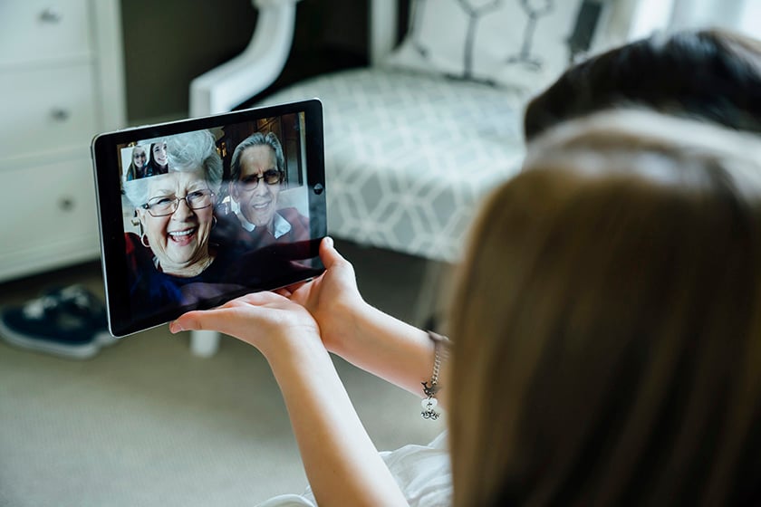 태블릿을 이용하여 조부모님과 화상 통화를 하고 있는 여성